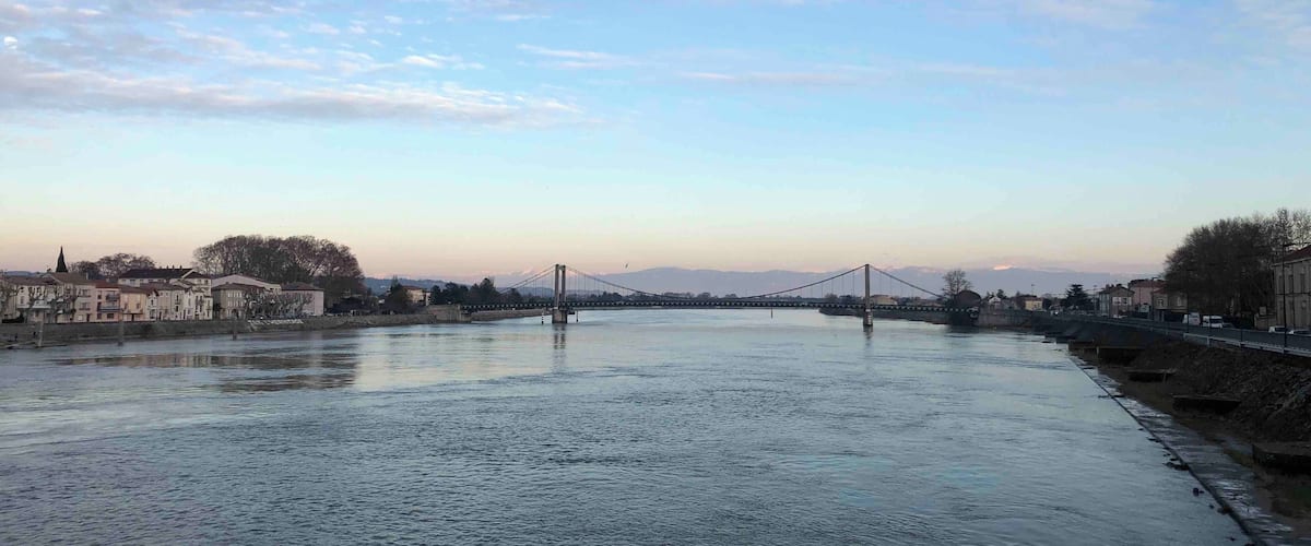 A river with a bridge, buildings, and trees in the background.