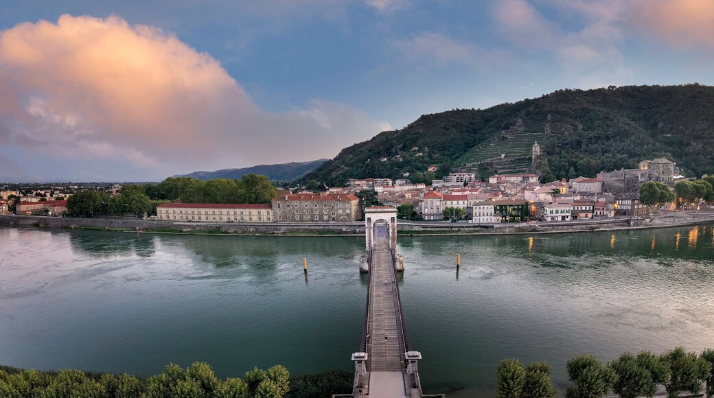 France, Ardeche, Tournon-sur-Rhone, Panorama of Passerelle Marc Seguin bridge and riverside town at dusk