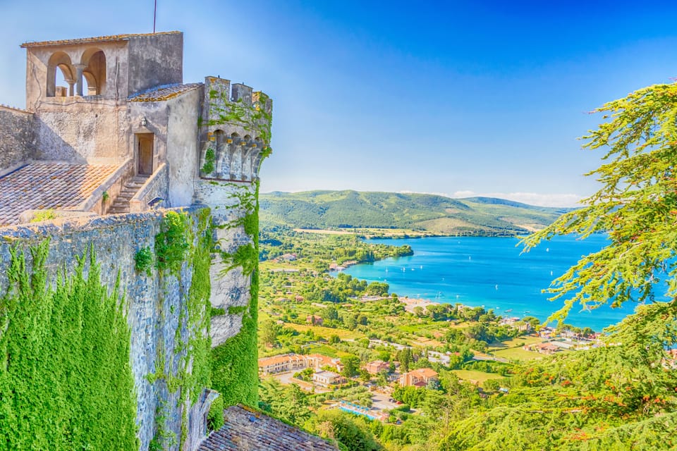 Una cittadina costiera con un'antica torre, vegetazione rigogliosa e una vista limpida sul mare.
