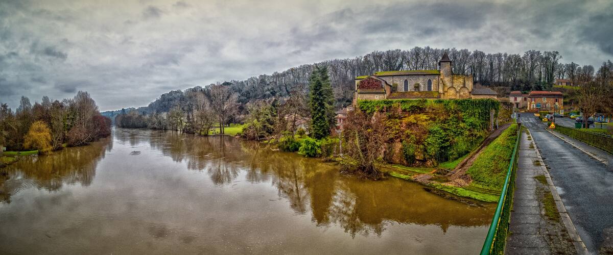 A river with a church on a hill and a road alongside.
