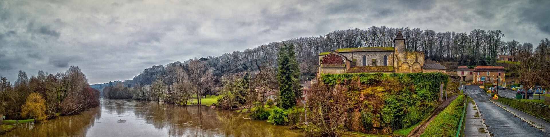 A river with a church on a hill and a road alongside.