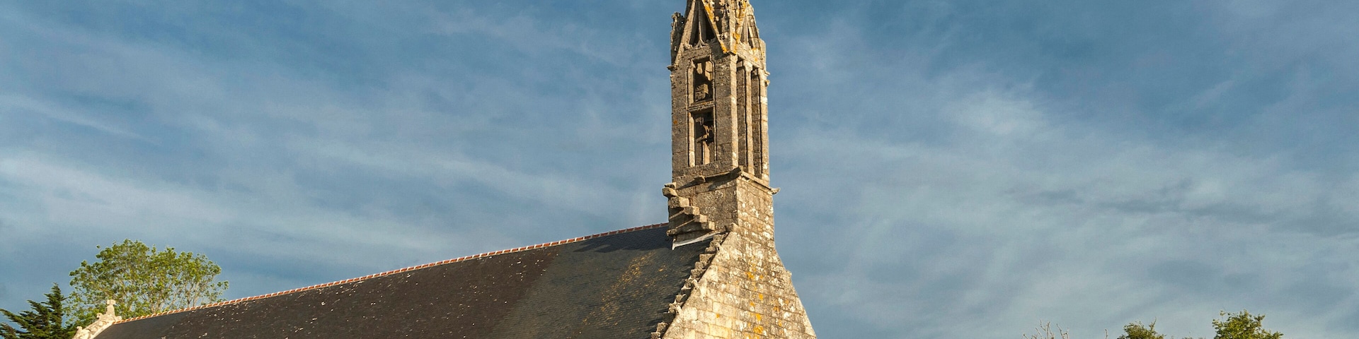 Una iglesia histórica con una aguja alta y un tejado de gran pendiente.