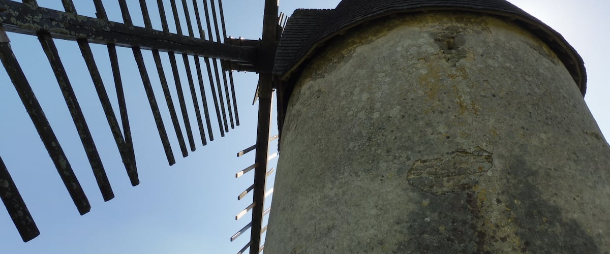 Een windmolen met een verweerde constructie en een puntige kap.