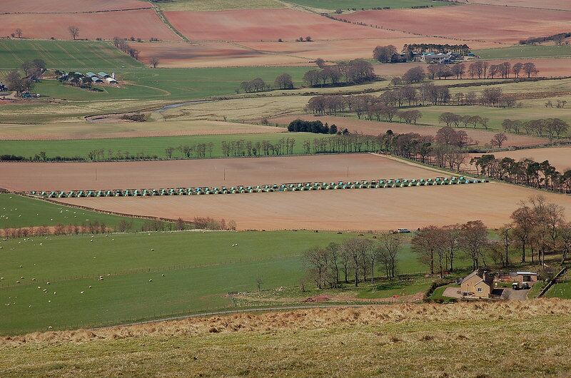 Field patterns in Lauderdale, Scottish Borders, Scotland. Fields near the Leader Water and a long line of plastic-wrapped bales as seen from the summit of Dabshead Hill. The reddish soil has been derived from Devonian sandstones and is characteristic of this eastern part of the Borders.