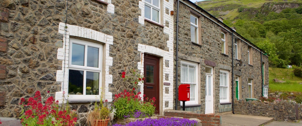 A stone house with a red door, white windows, and a red mailbox.