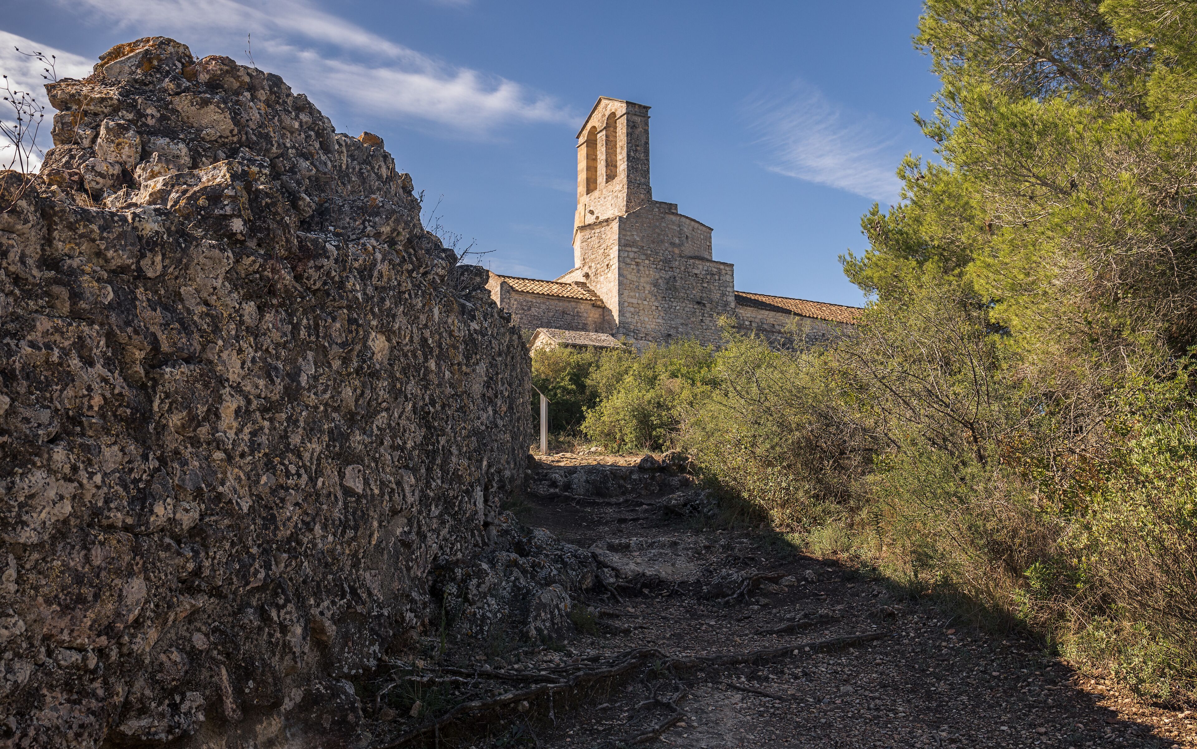 A stone tower with a tiled roof amidst rocky terrain and sparse vegetation.