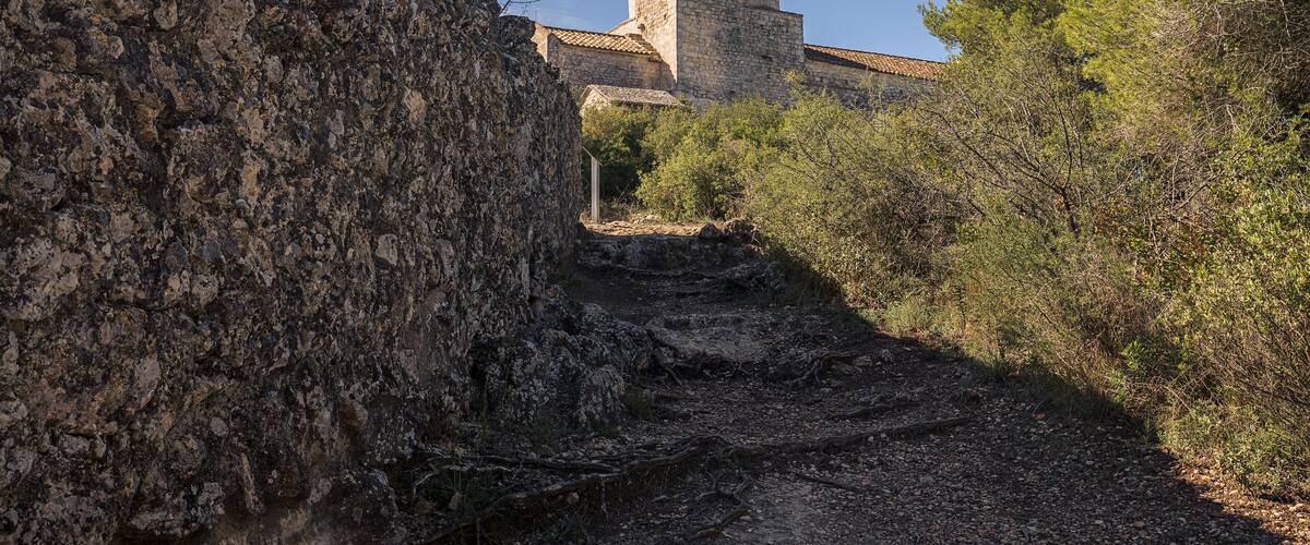 A stone tower with a tiled roof amidst rocky terrain and sparse vegetation.
