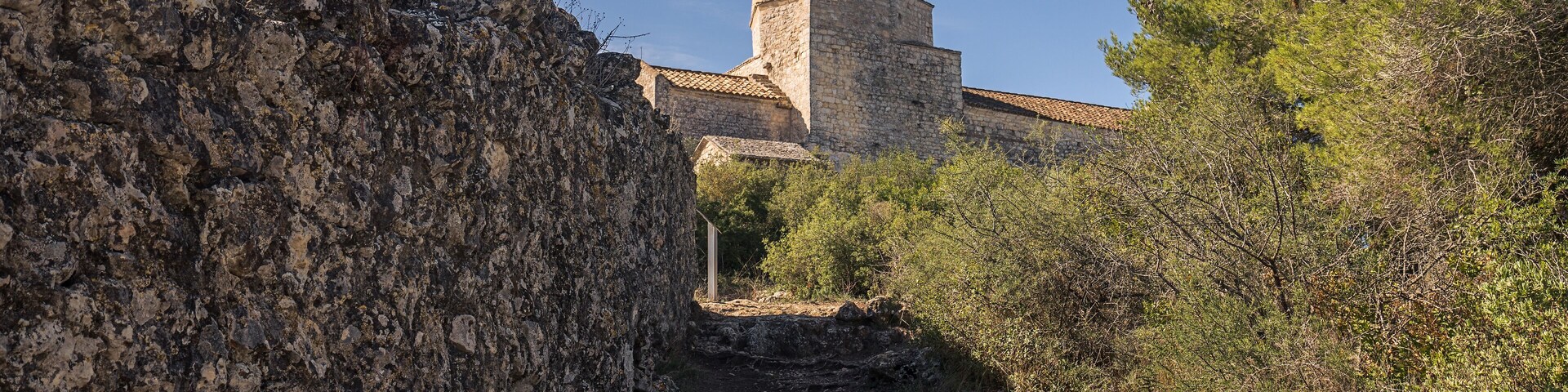 A stone tower with a tiled roof amidst rocky terrain and sparse vegetation.