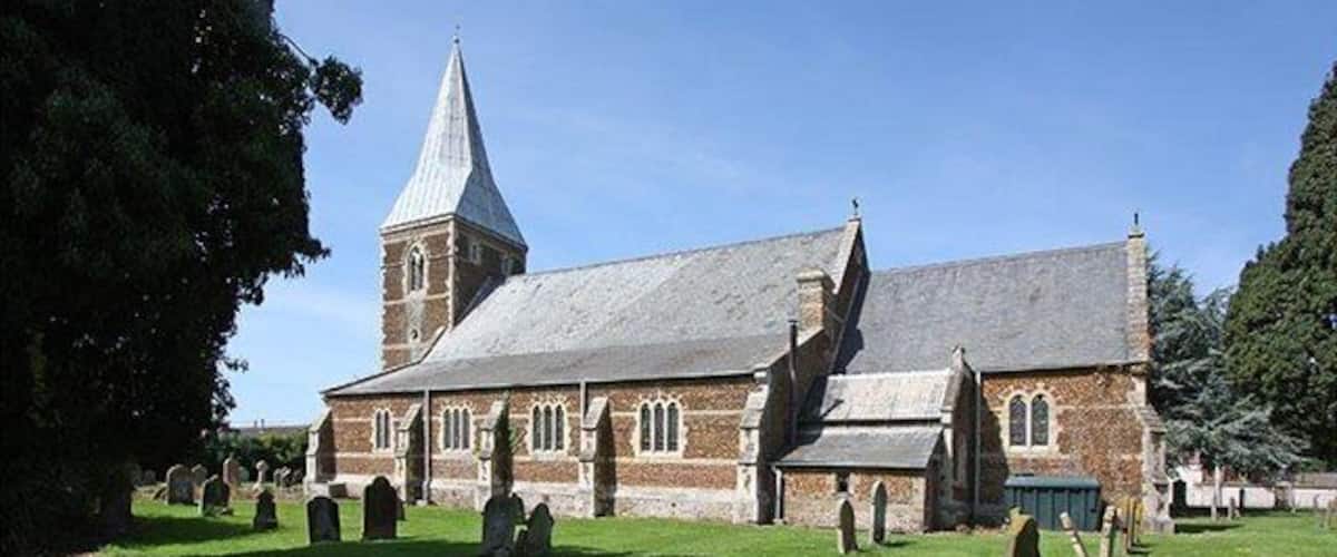 A church with a tall steeple and a graveyard in front.