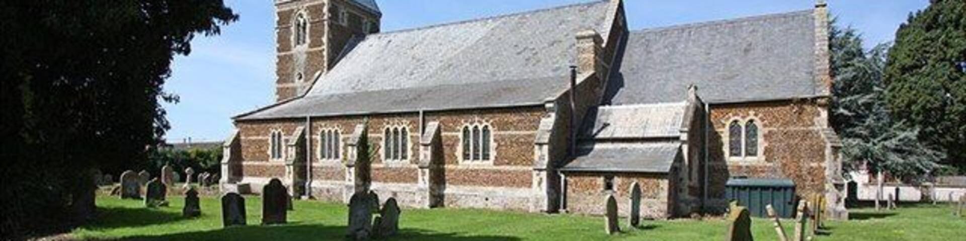 A church with a tall steeple and a graveyard in front.