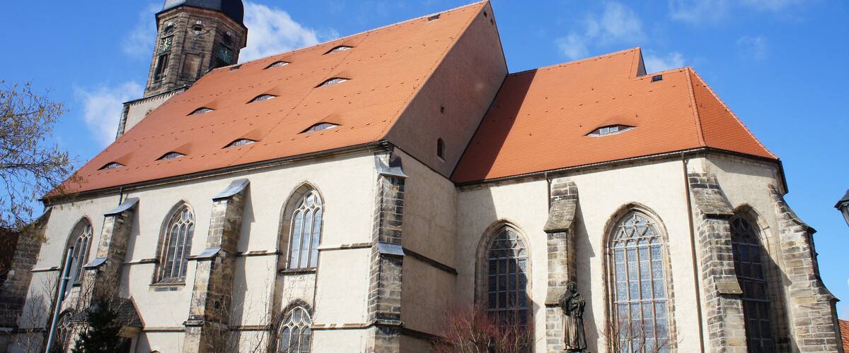 A church with a red-tiled roof and a tower with a weather vane.