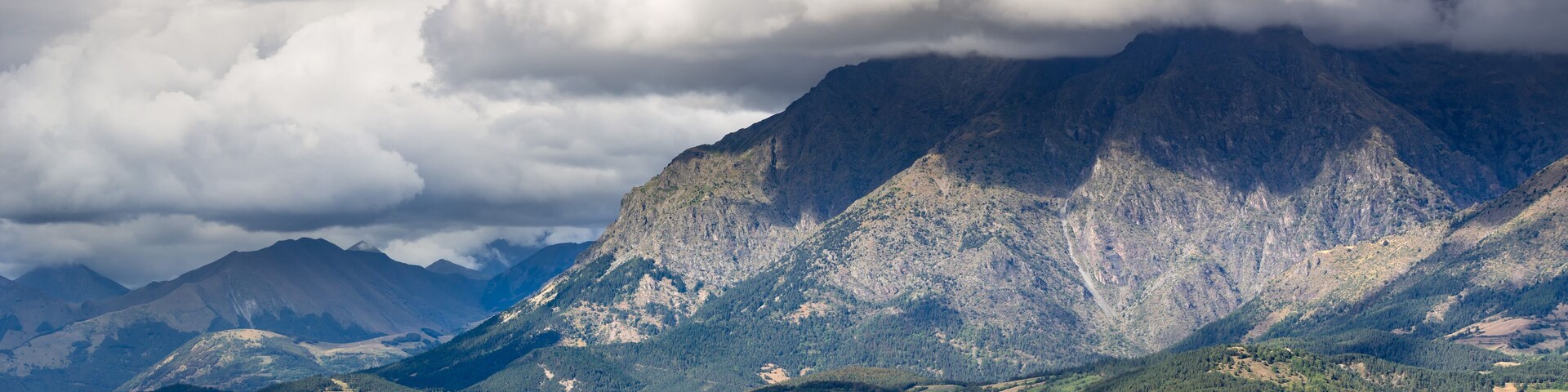 Saint Bonnet en Champsaur and the Petit Chaillol mountain peak in the clouds. Summer in the Southern French Alps. Hautes-Alpes, PACA Region, Champsaur, France