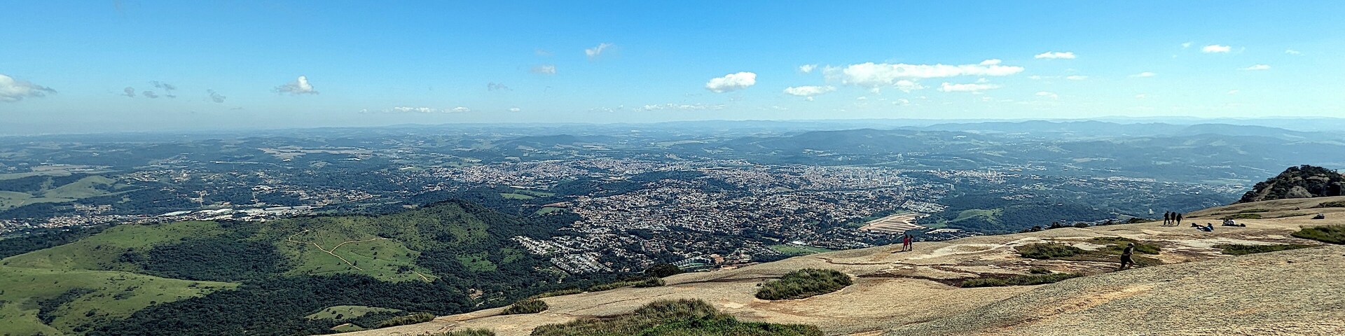 A panoramic view of a city from a hilltop with a clear sky.