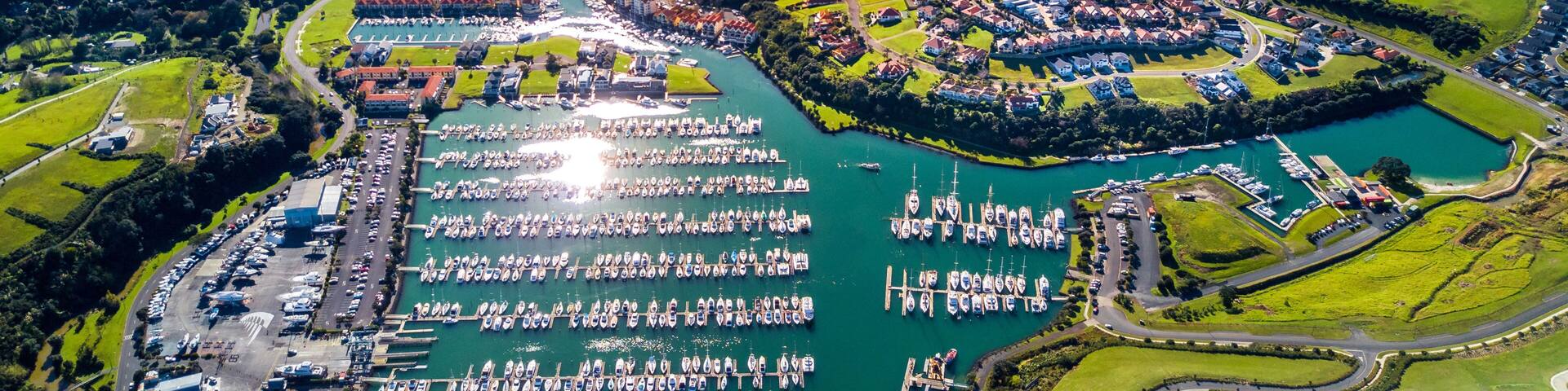 Aerial view on residential suburbs surrounded by sunny ocean harbour. Whangaparoa peninsula, Auckland, New Zealand
