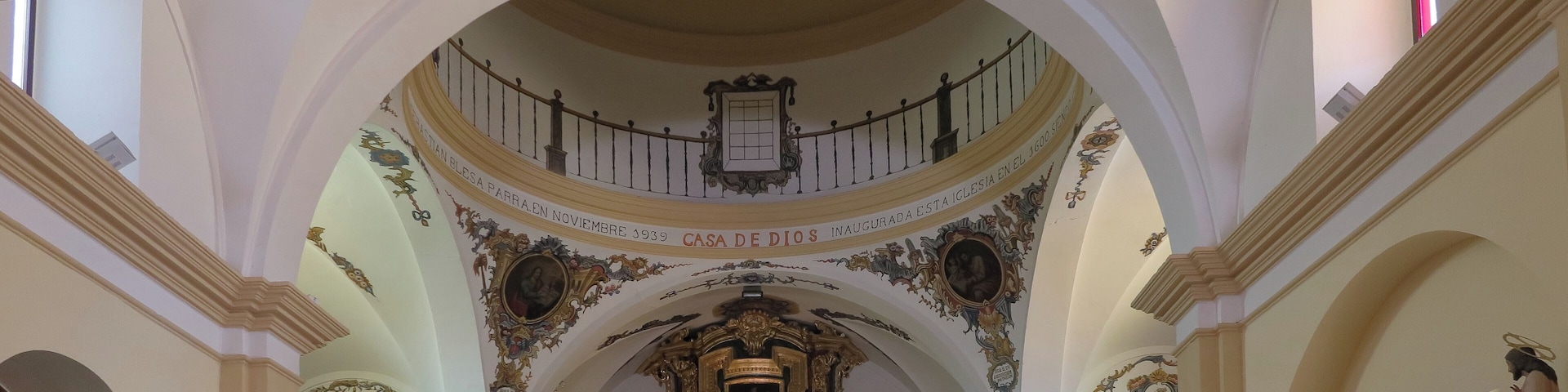 Interior de igreja ricamente decorado, com teto alto e ornamentos detalhados, e um altar central.