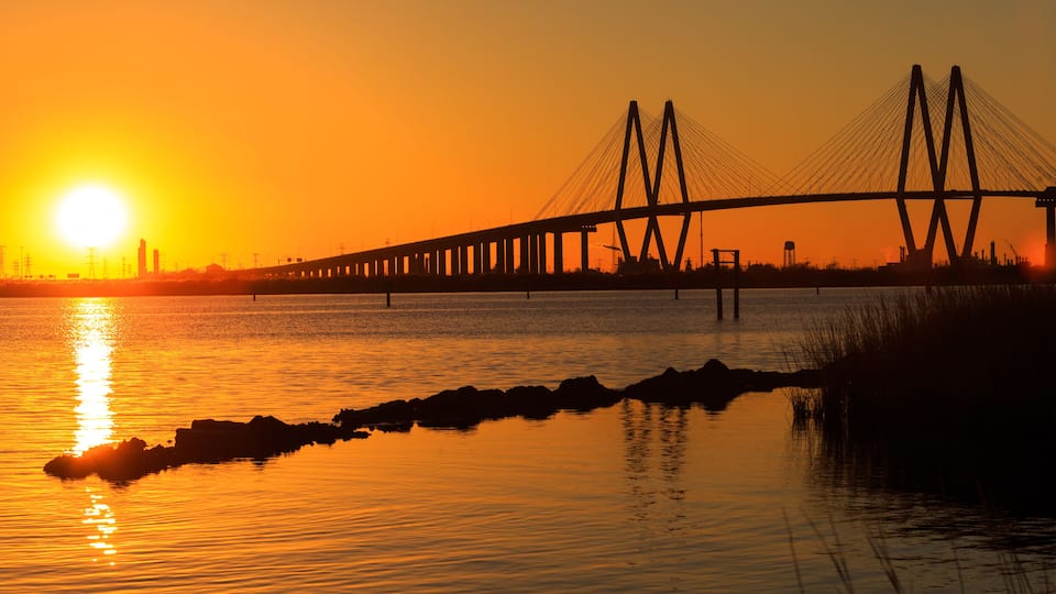 A bridge at sunset with the sun reflecting on the water.