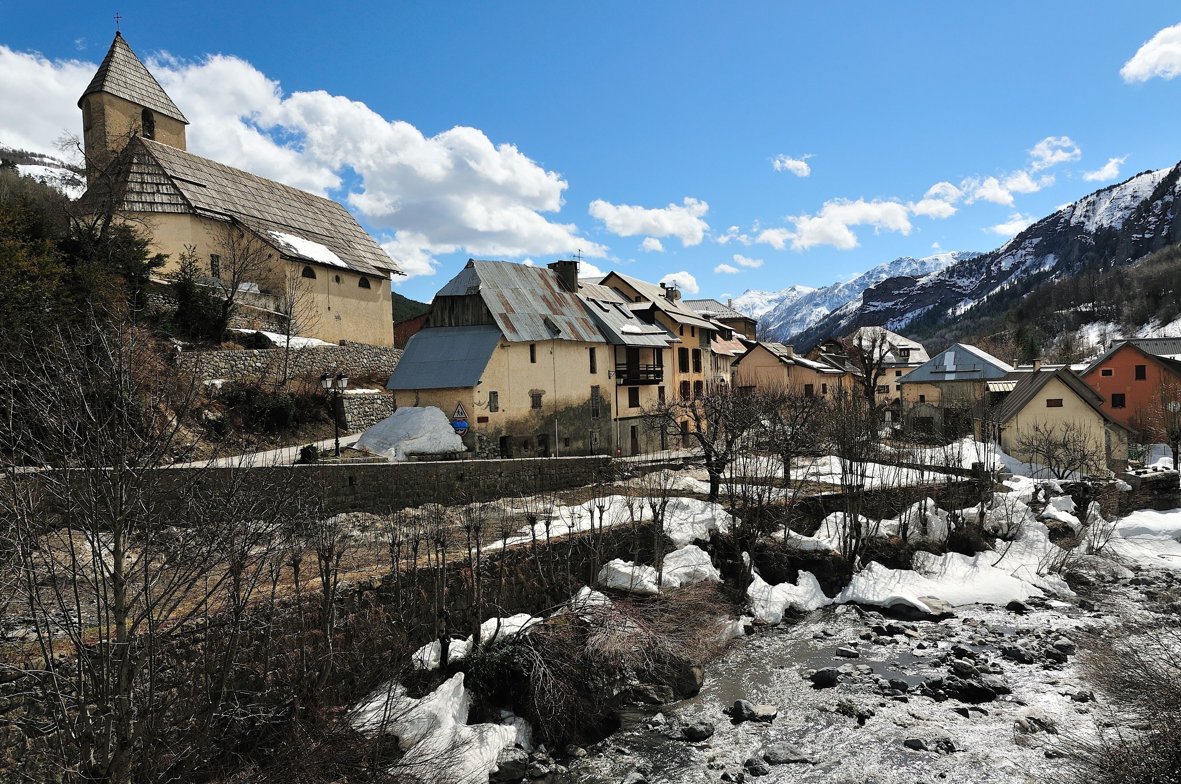 A snow-covered village with a church, houses, and mountains in the background.