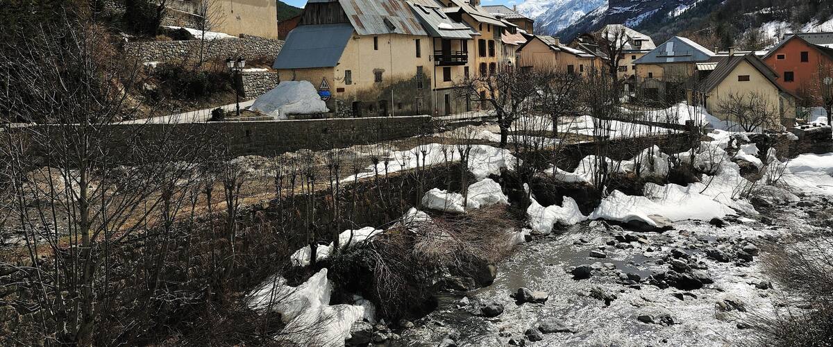 A snow-covered village with a church, houses, and mountains in the background.