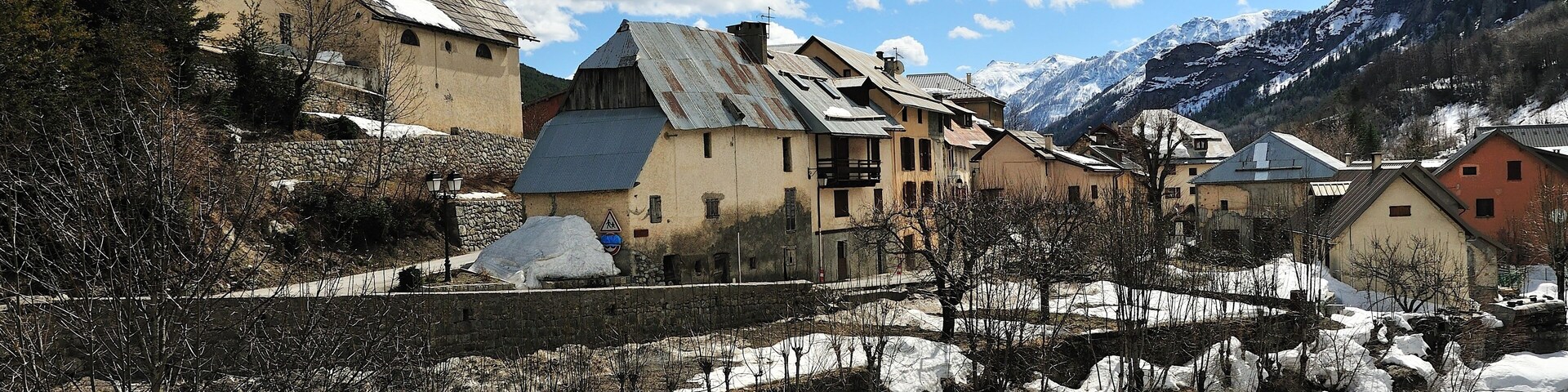 A snow-covered village with a church, houses, and mountains in the background.