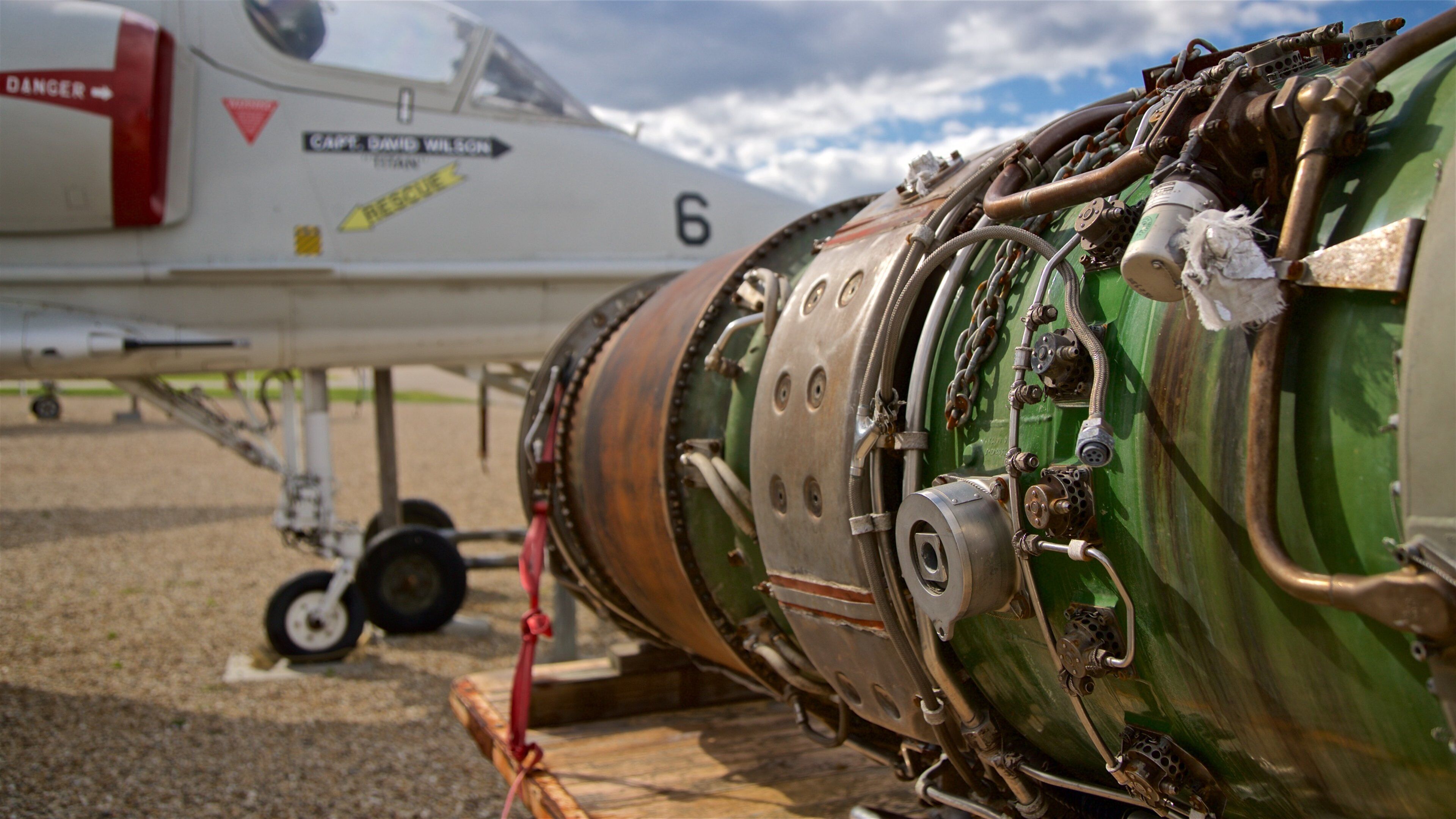 A close-up of a jet engine with visible wear and tear, a warning label, and a rescue arrow.