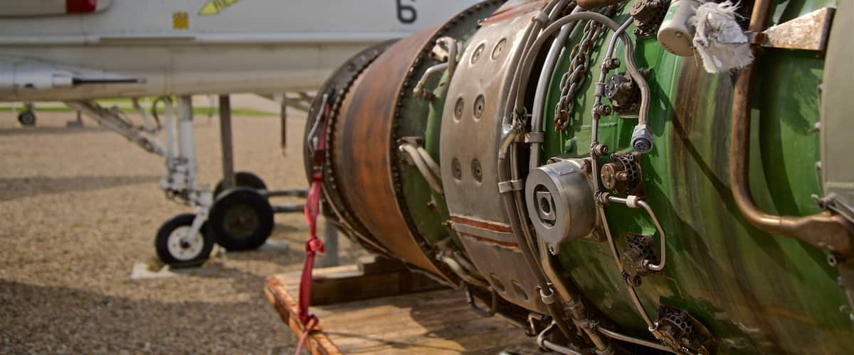 A close-up of a jet engine with visible wear and tear, a warning label, and a rescue arrow.