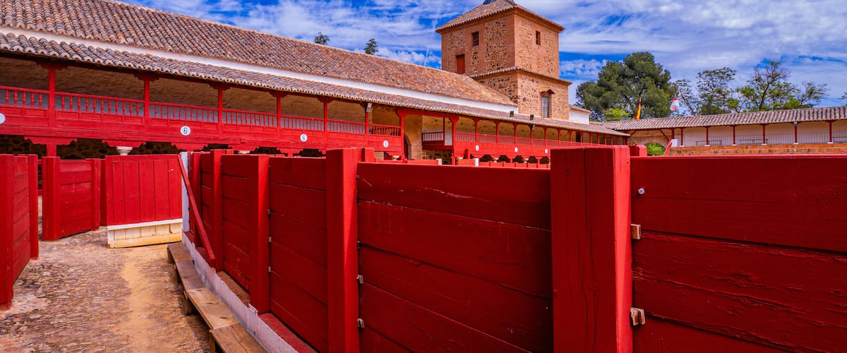 A red-roofed building with a tower, surrounded by red wooden fences.