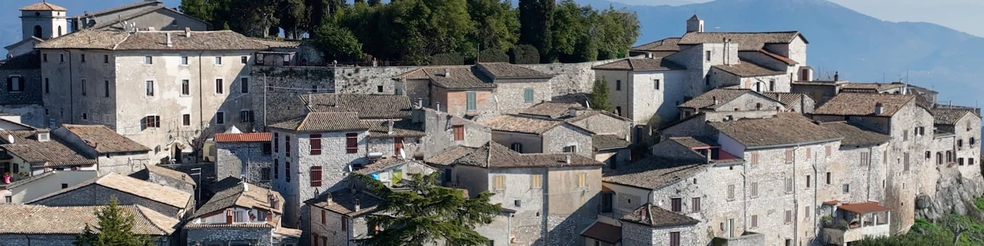 A historic town with stone buildings and a mountainous backdrop.