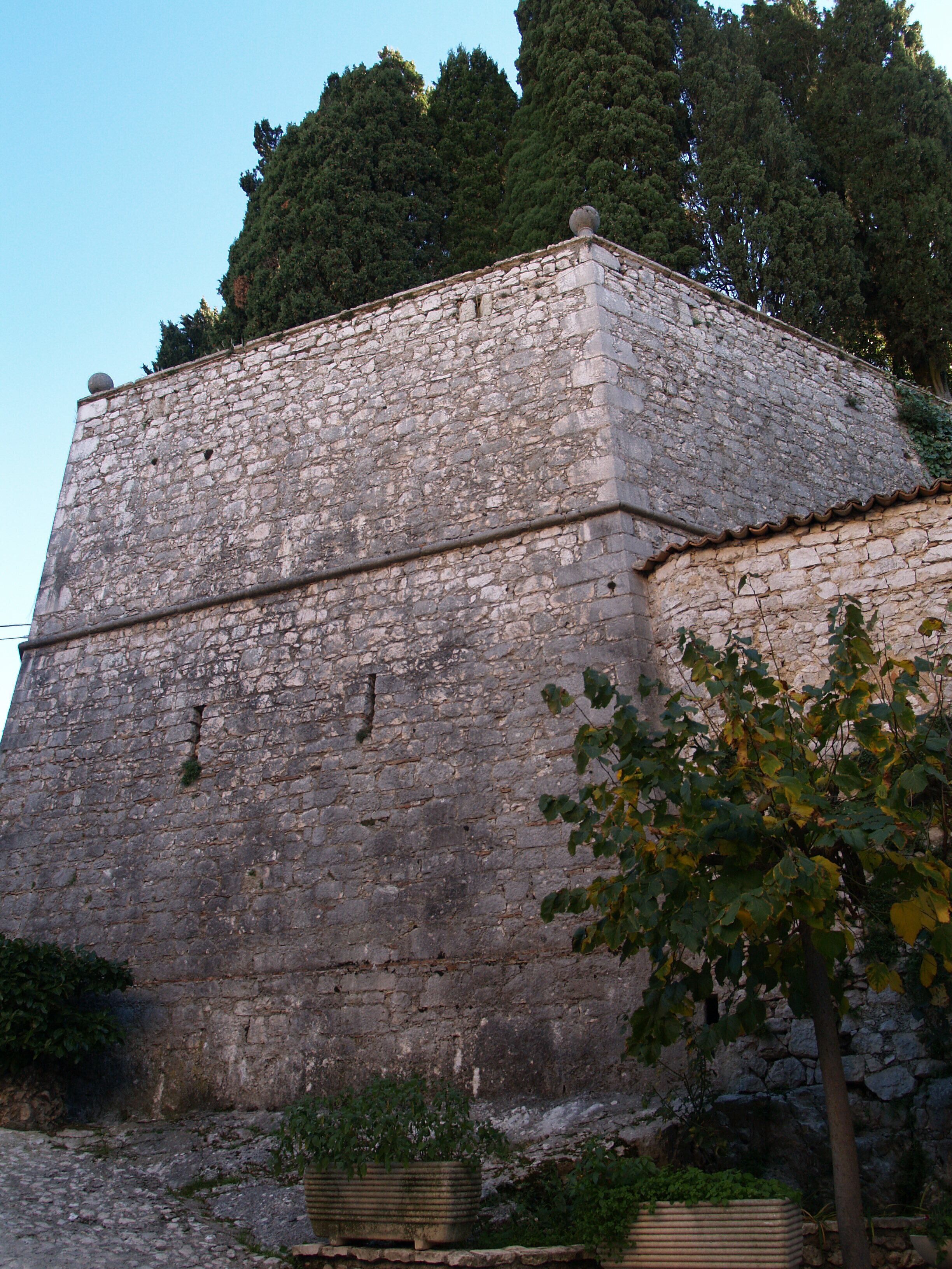 A stone wall with a tree in the foreground.