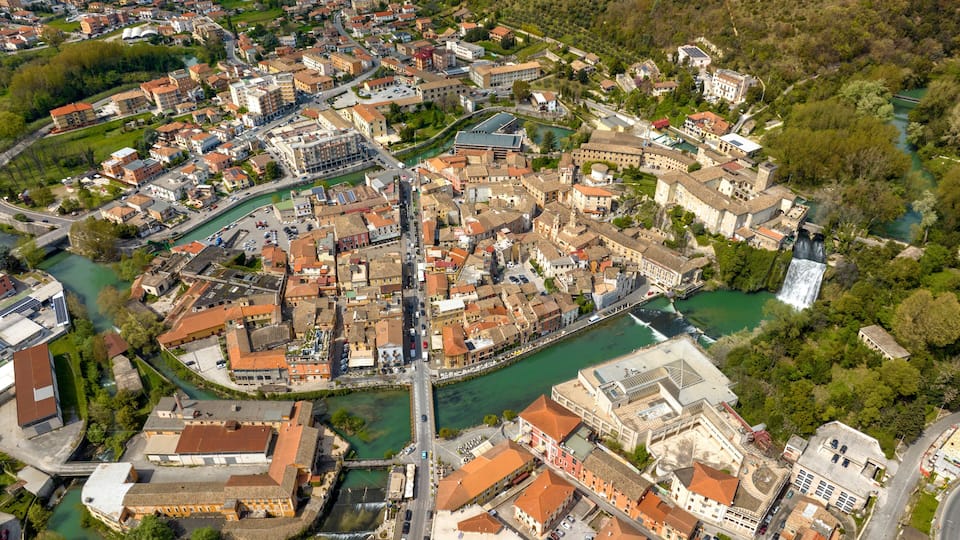 An aerial view of a historic town with a river, buildings, and a waterfall.