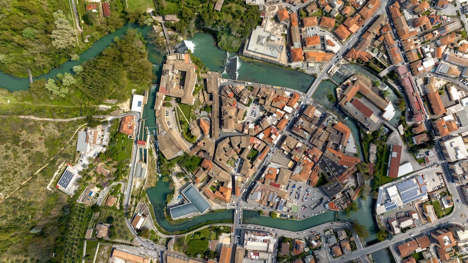 An aerial view of a historic town with a river, bridges, and dense architecture.