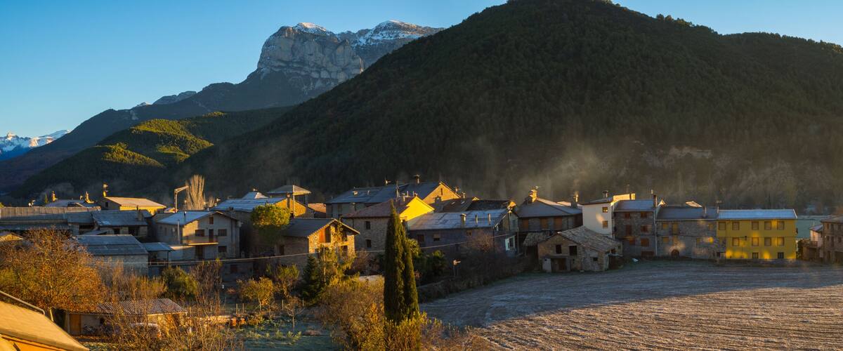 A village with stone houses and a mountain in the background.