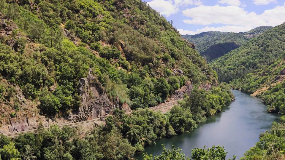 A river winding through a mountainous landscape with dense greenery and rocky cliffs.