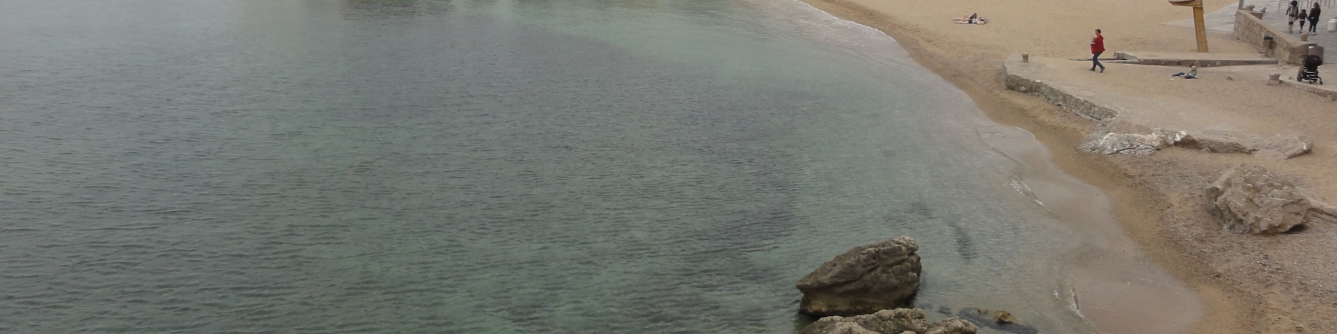 Un pueblo costero con playa de arena, aguas claras y afloramientos rocosos.
