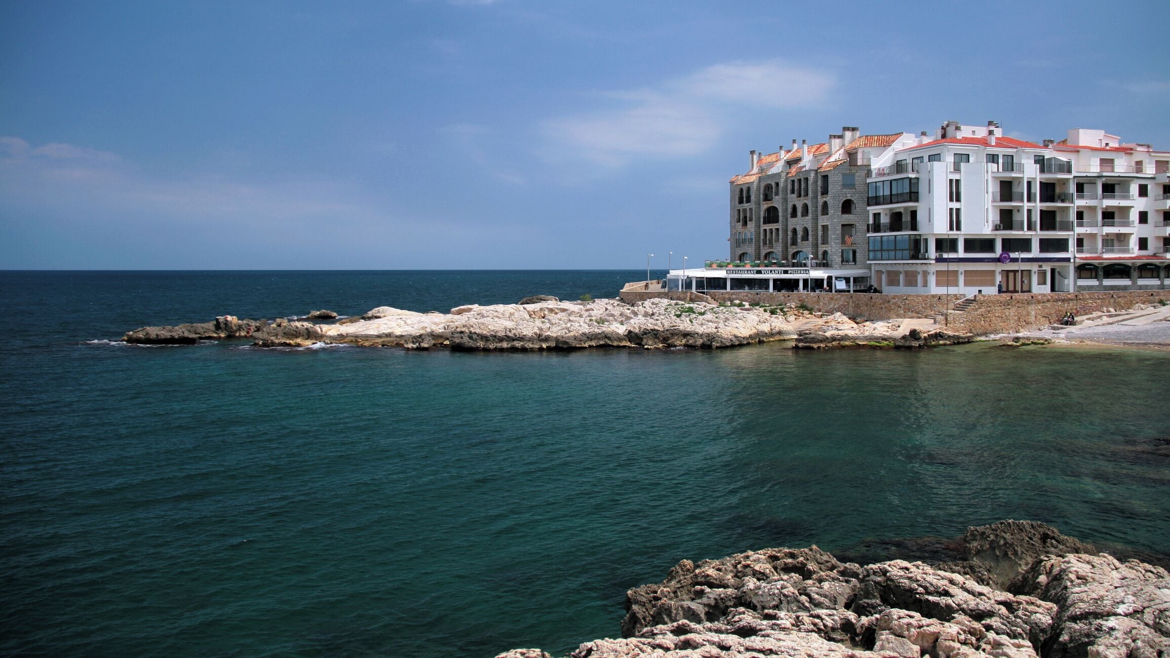 A coastal building with a restaurant and a rocky shoreline.