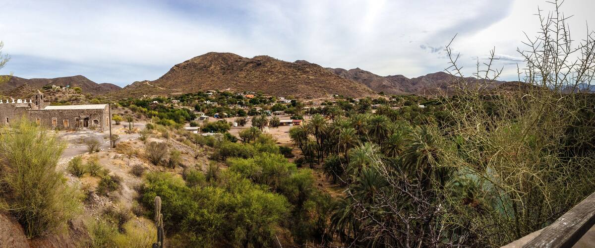 A mountainous landscape with a small stone building and scattered houses.
