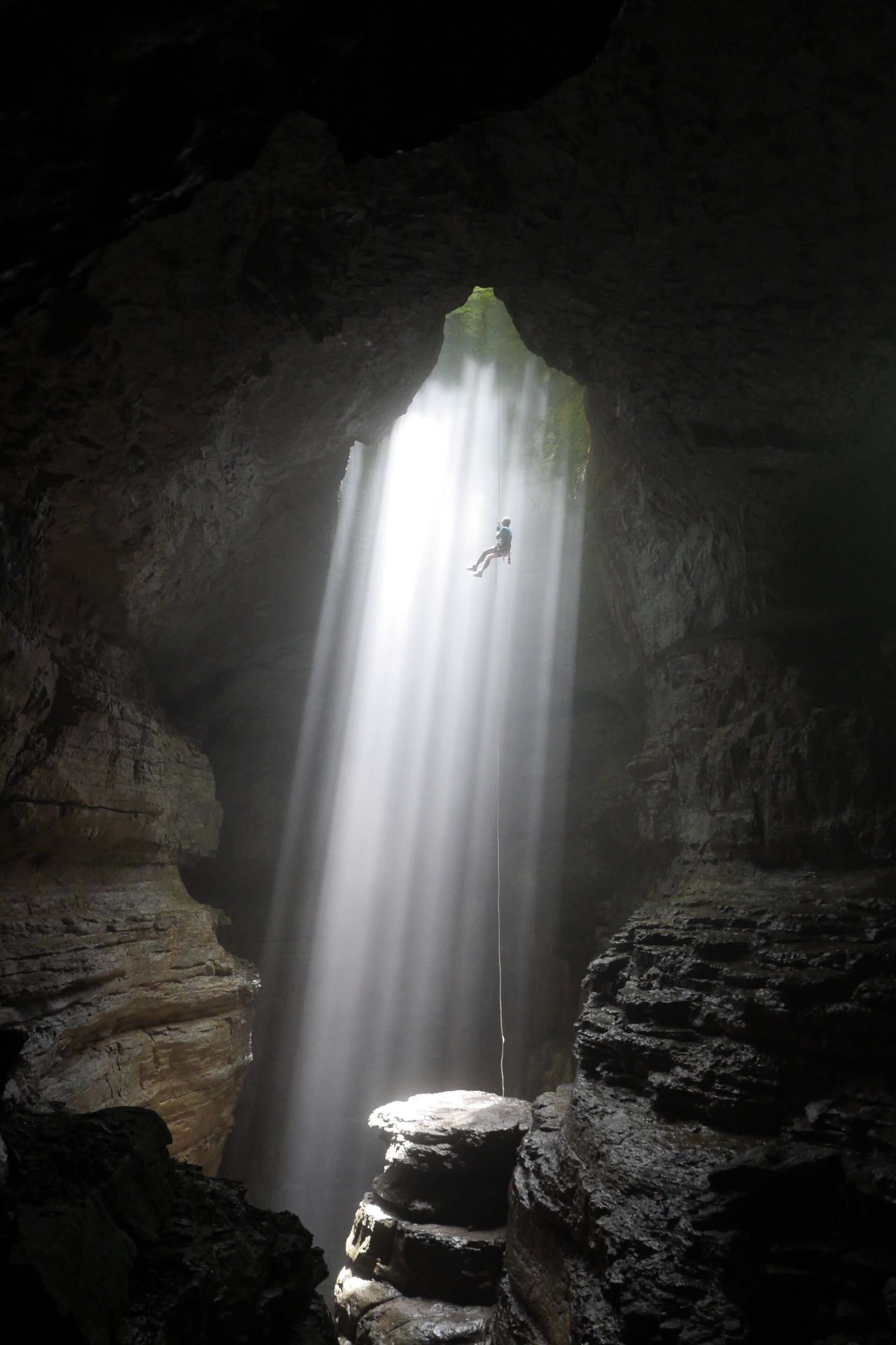 A person rappelling down a waterfall in a cave.
