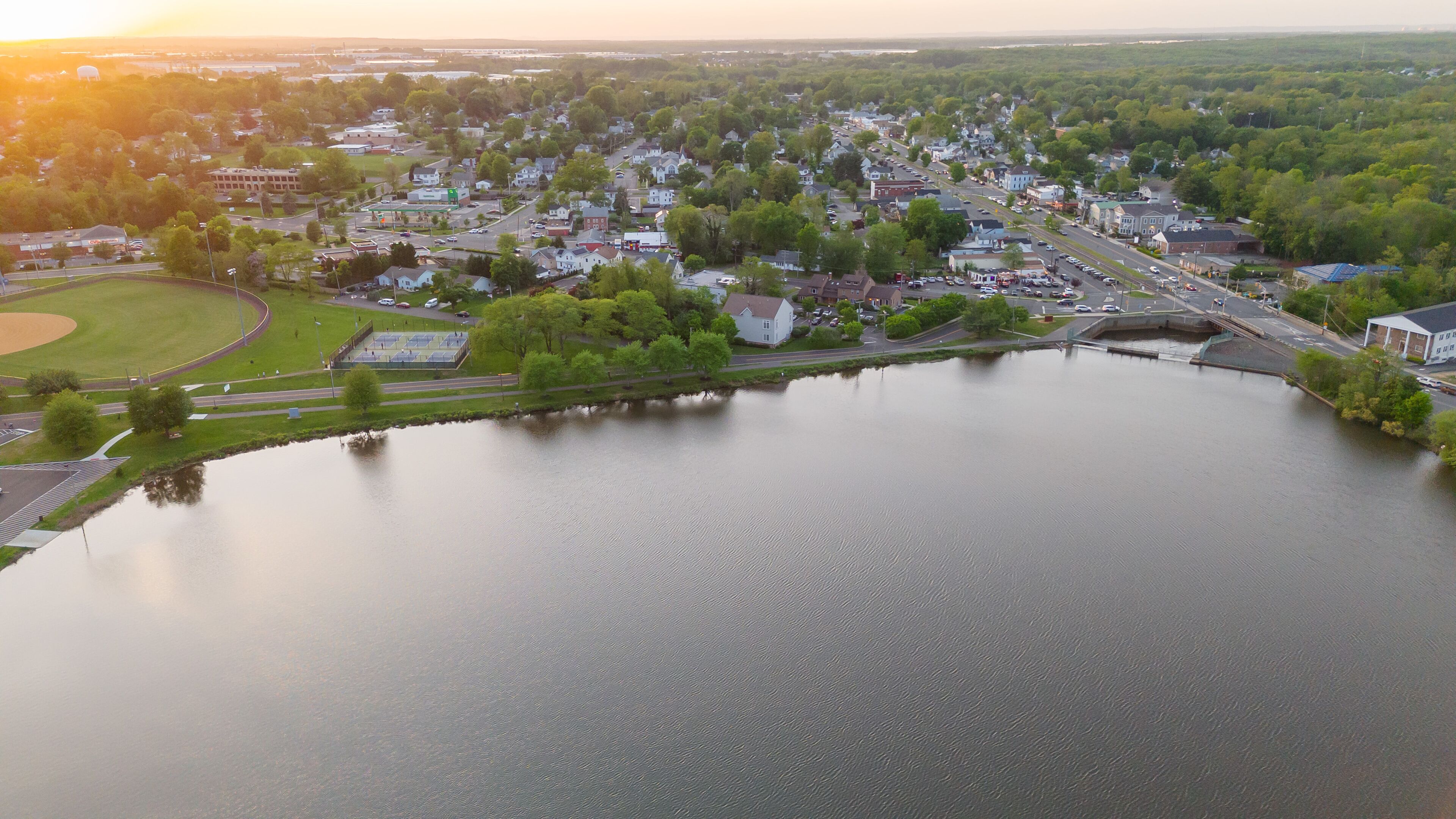 A river flowing through a town with houses and a baseball field.