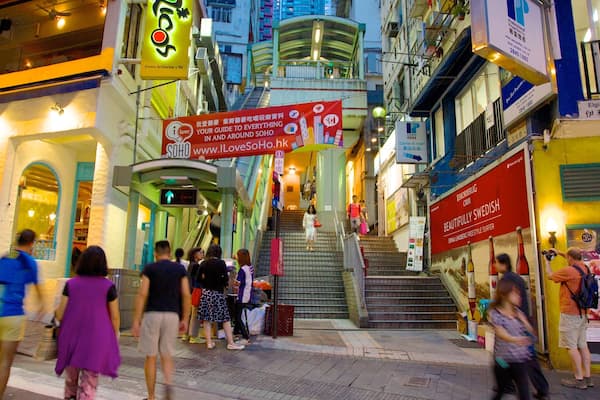 A busy urban street with people walking, a staircase, and various shops and signs.