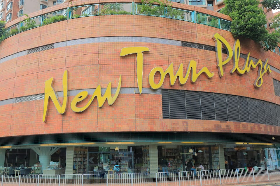 Un edificio con facciata curva e la scritta 'New Town Plaza'.