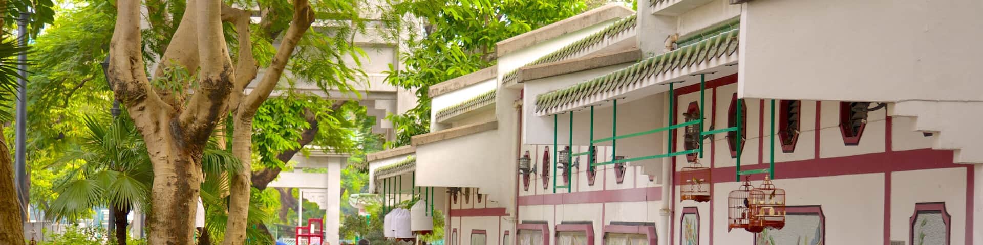 A bustling street lined with traditional buildings, pedestrians, and lush greenery.