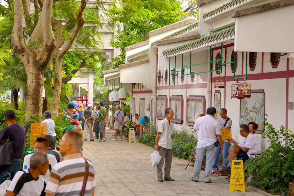 A bustling street lined with traditional buildings, pedestrians, and lush greenery.