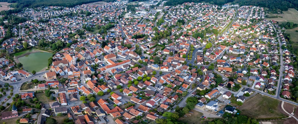 An aerial view of a densely populated residential area with numerous houses, roads, and green spaces.
