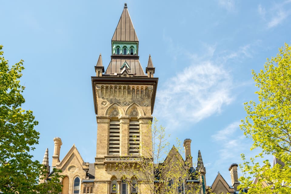 A historic building with a prominent tower, arched windows, and a pointed roof.