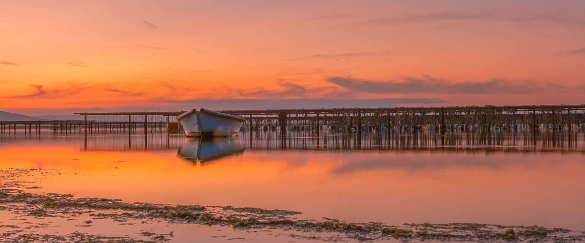 A sunset over a calm lake with a wooden pier extending into the water.