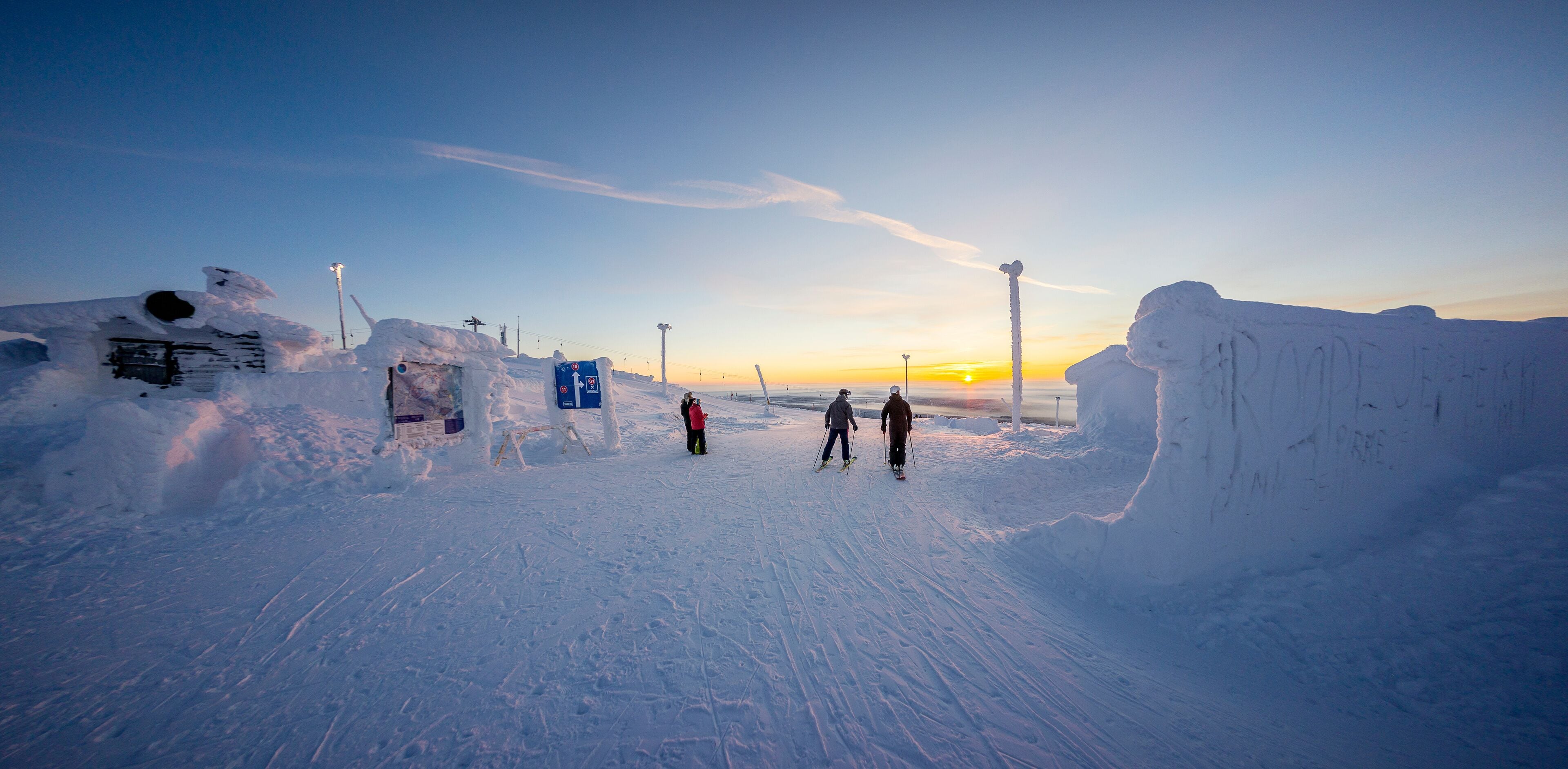 Un paisaje nevado con un atardecer, un telesilla y un sendero cubierto de nieve.