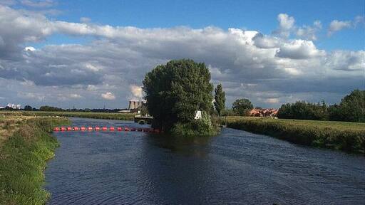 Beal- The River Aire. This photograph is taken from the Bridge over the River Aire at Beale, looking west. Eggborough Power Station can be seen on the horizon. The river is not navigable to the left of the island in the picture. There is a weir. To the right of the island is navigable via a lock.