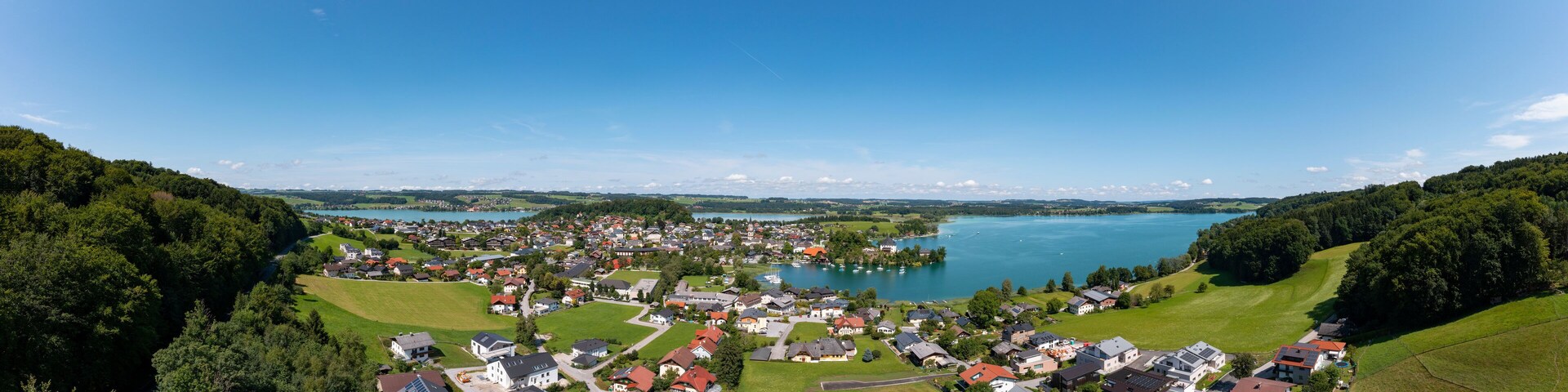 A lakeside village with houses, green fields, and a large lake.