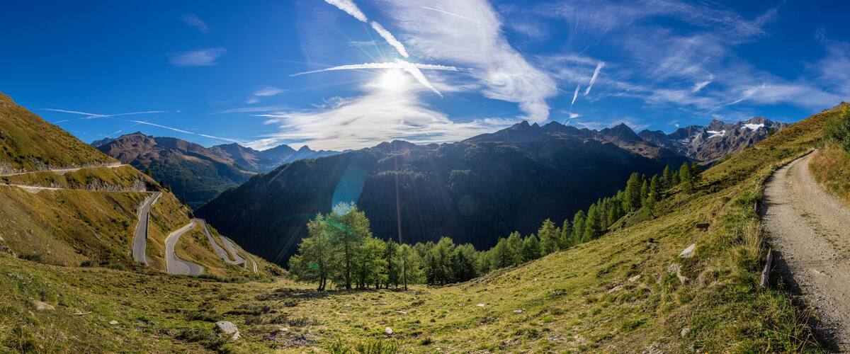 A mountain landscape with a winding road, a clear sky, and a valley.