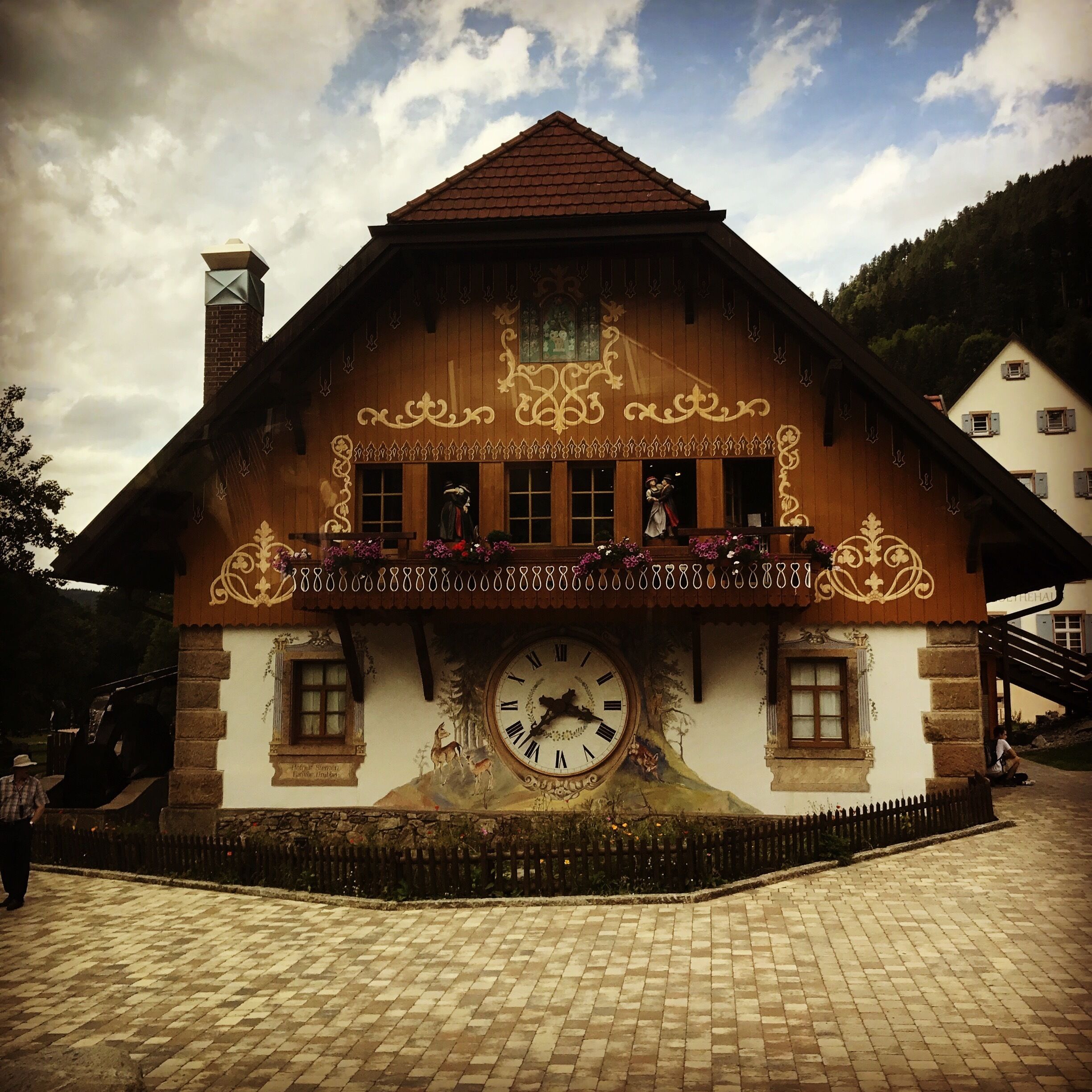 A traditional wooden house with a clock, ornate decorations, and a balcony.