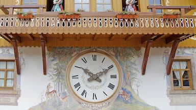 A building with a large clock, wooden balconies, and decorative murals.